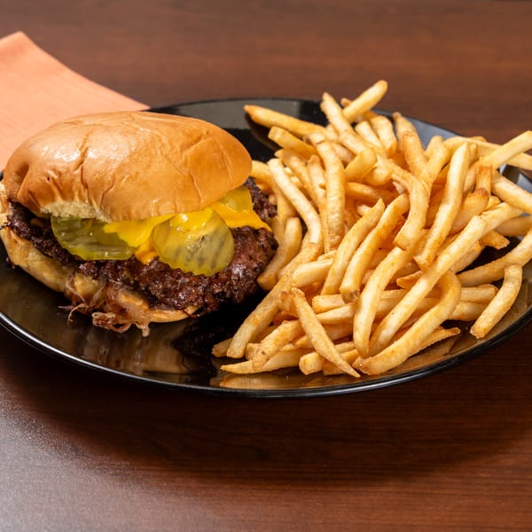 Cheeseburger with pickles and caramelized onions, served with a side of golden french fries.